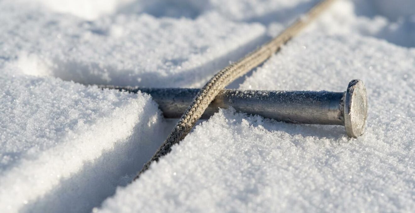 Vue macro de la technique d'ancrage T-slot avec sardine enterrée horizontalement dans la neige