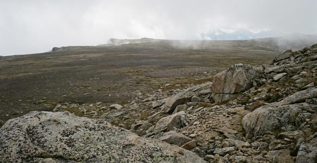 Vaste étendue minérale d'altitude avec rochers et pierres sous une lumière douce, ambiance contemplative et apaisante