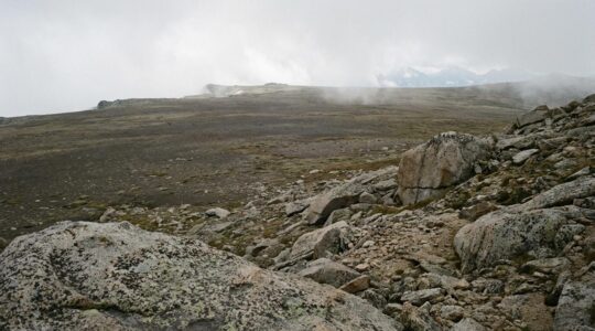 Vaste étendue minérale d'altitude avec rochers et pierres sous une lumière douce, ambiance contemplative et apaisante